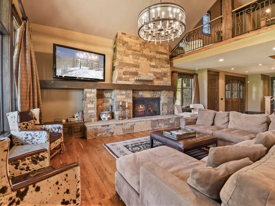 Living room seating faces a stone fireplace beneath a chandelier.