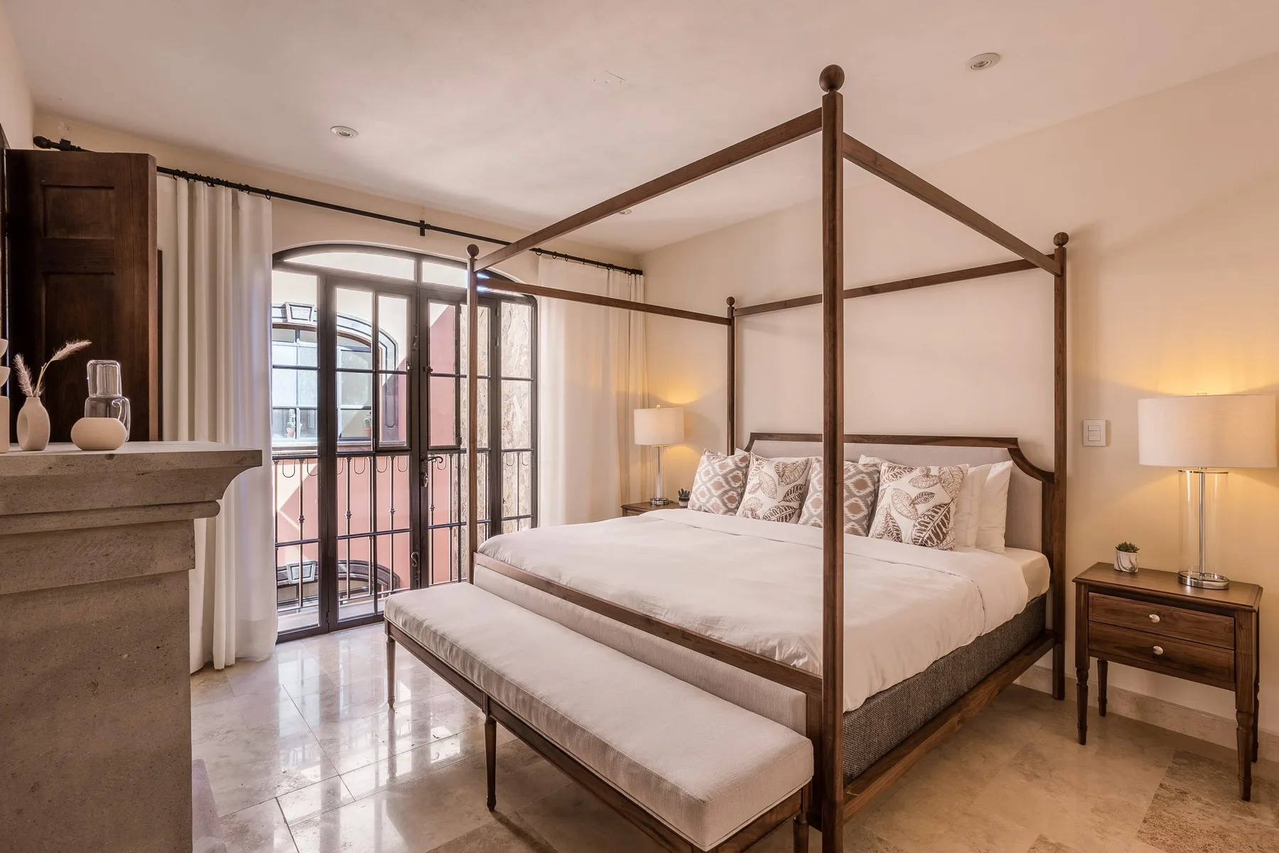 A bedroom with a four-poster bed and a cushioned bench at its foot.