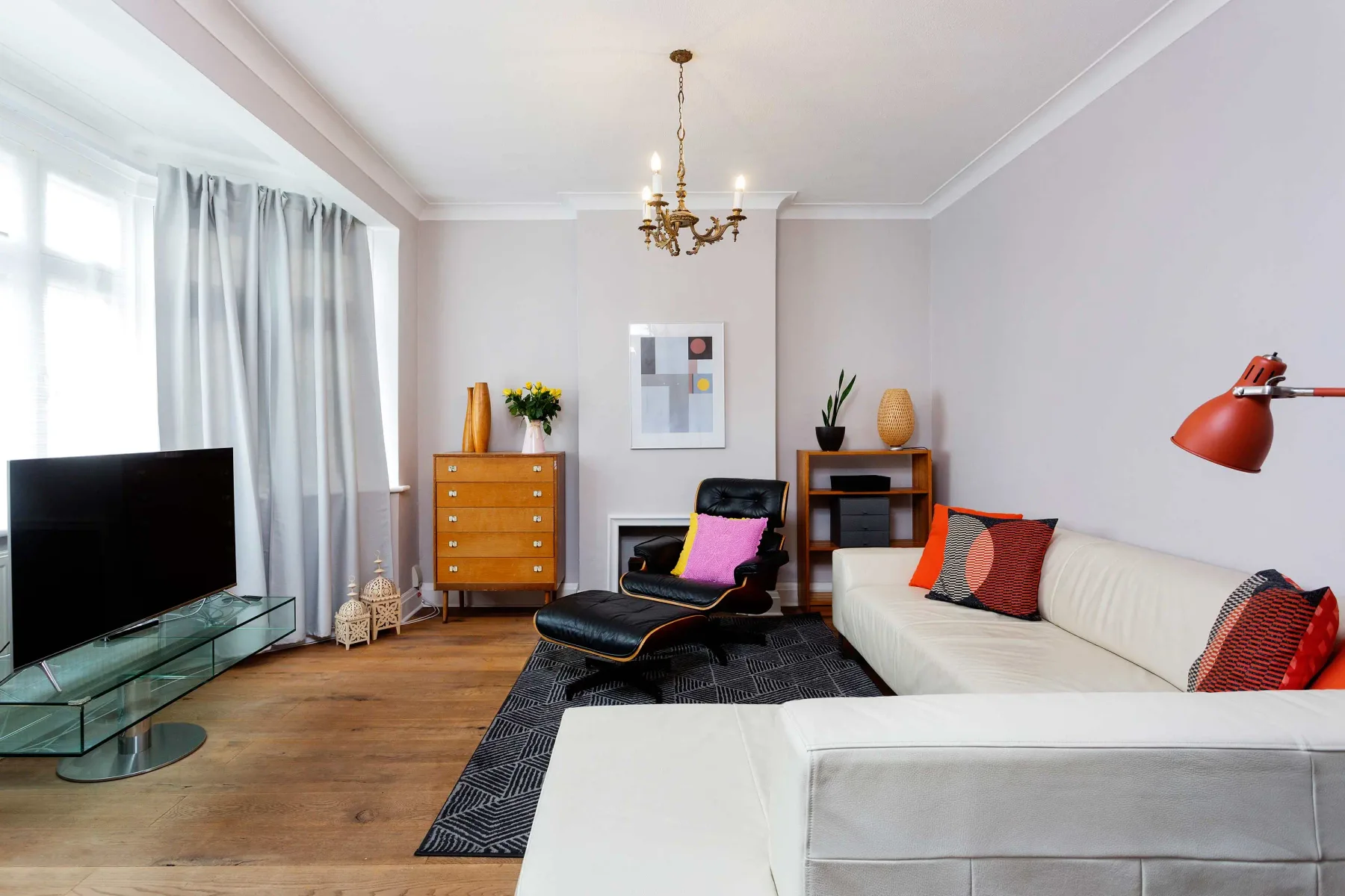 Una sala luminosa con un sofá seccional blanco y un televisor.