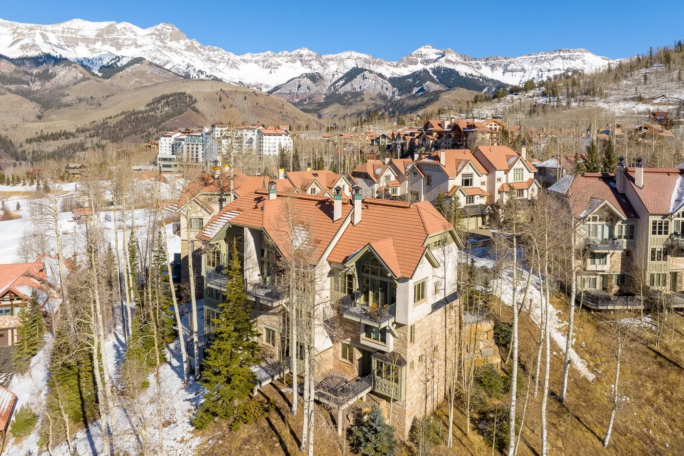 Aerial view of mountain lodges with snow-dusted peaks in the background.
