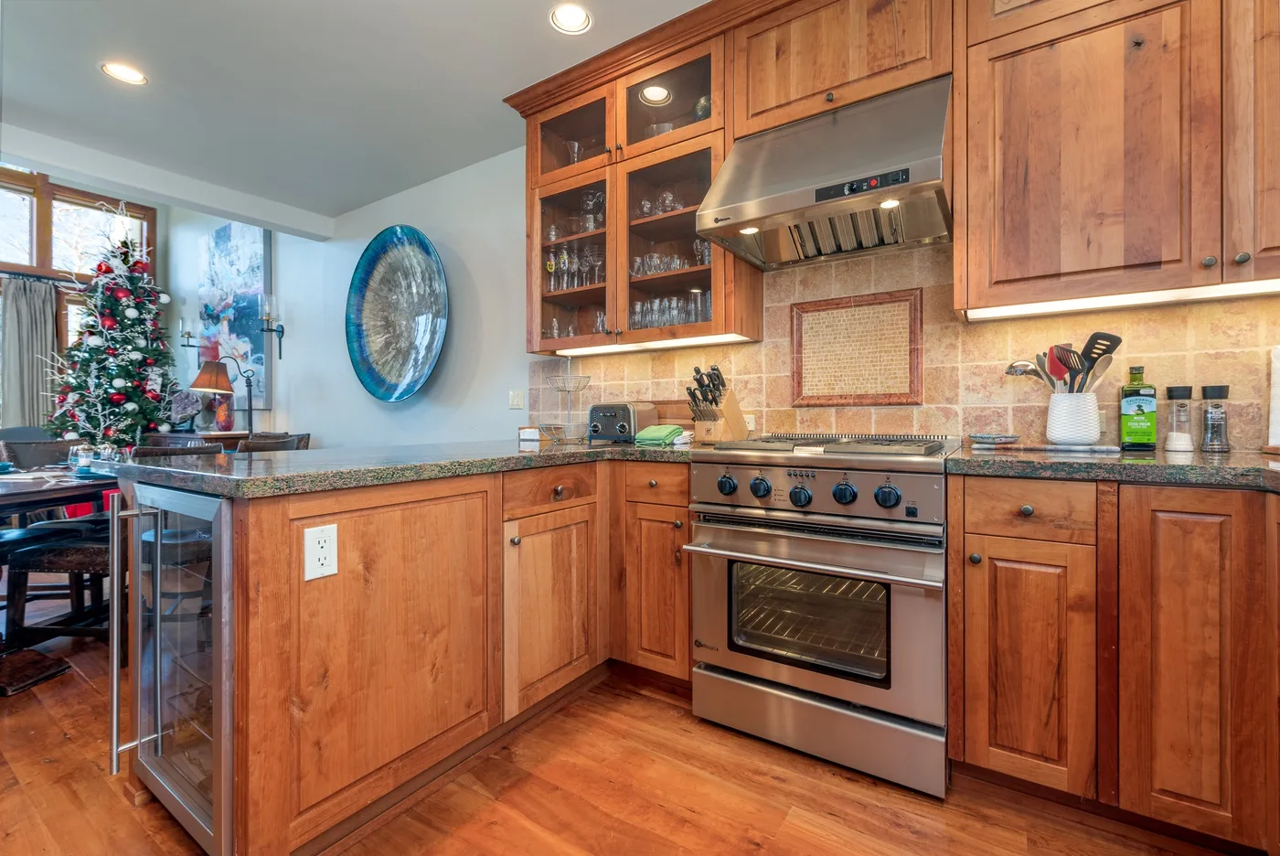 A warm-toned kitchen with wooden cabinets, a central island, and stainless steel appliances.