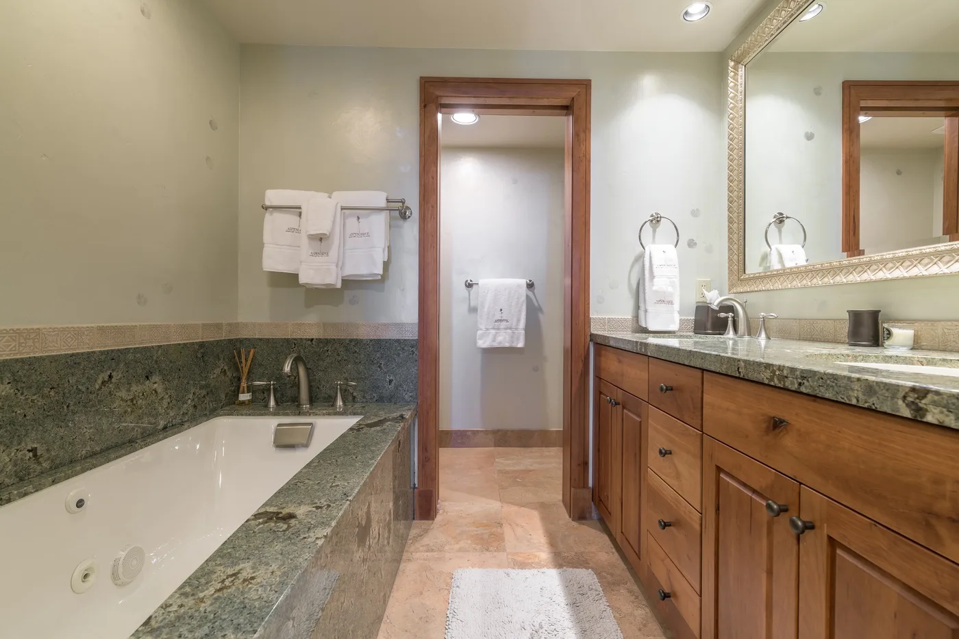A bathroom with a bathtub, a long vanity, and a doorway.