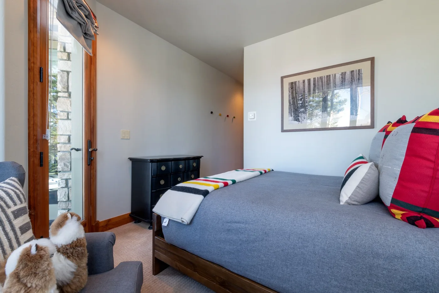 A bedroom with a gray bed and a framed picture on the wall.
