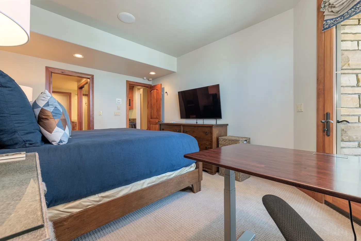 A bedroom with a bed, television, and table.