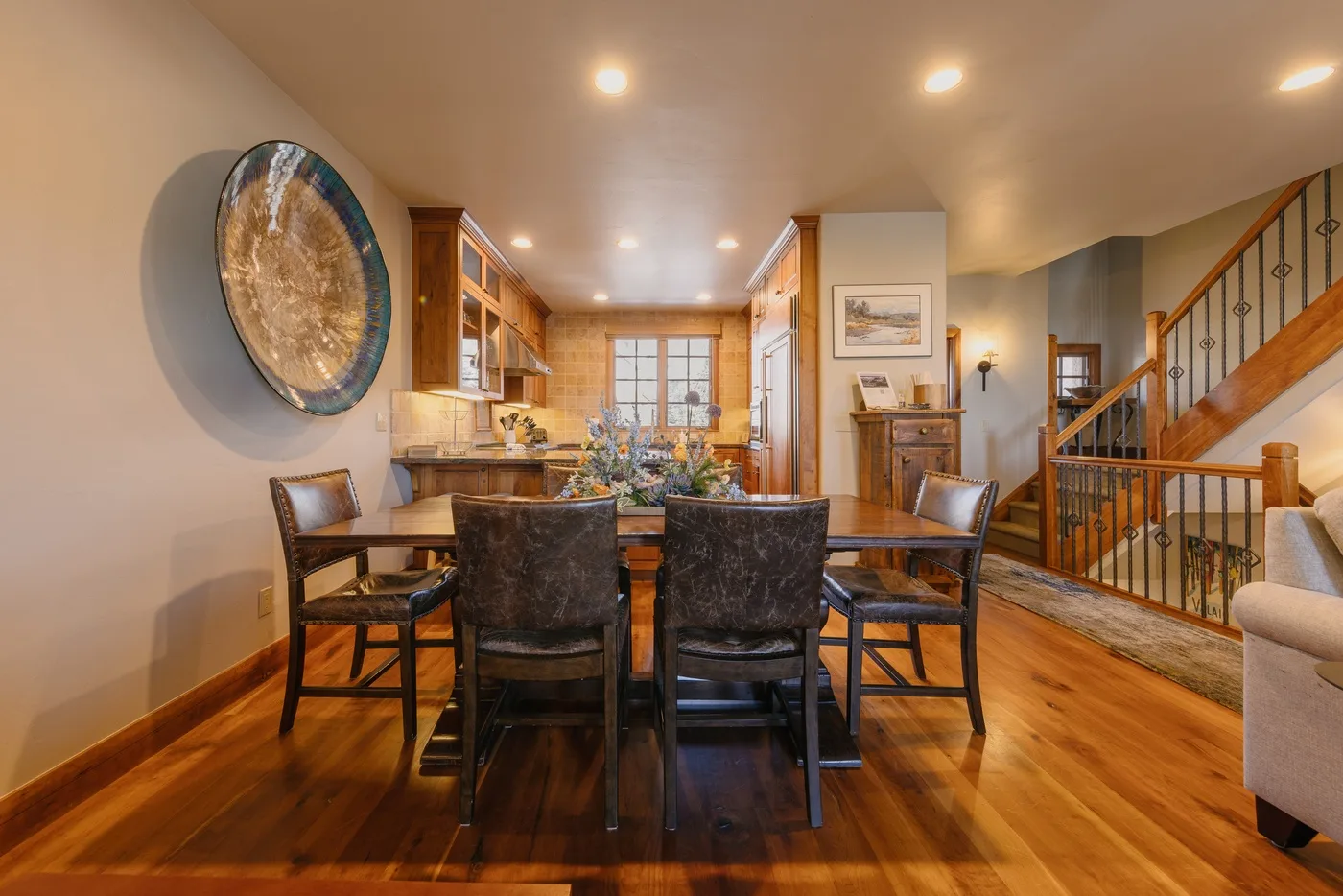 A dining room with a table and chairs beside a wooden staircase.