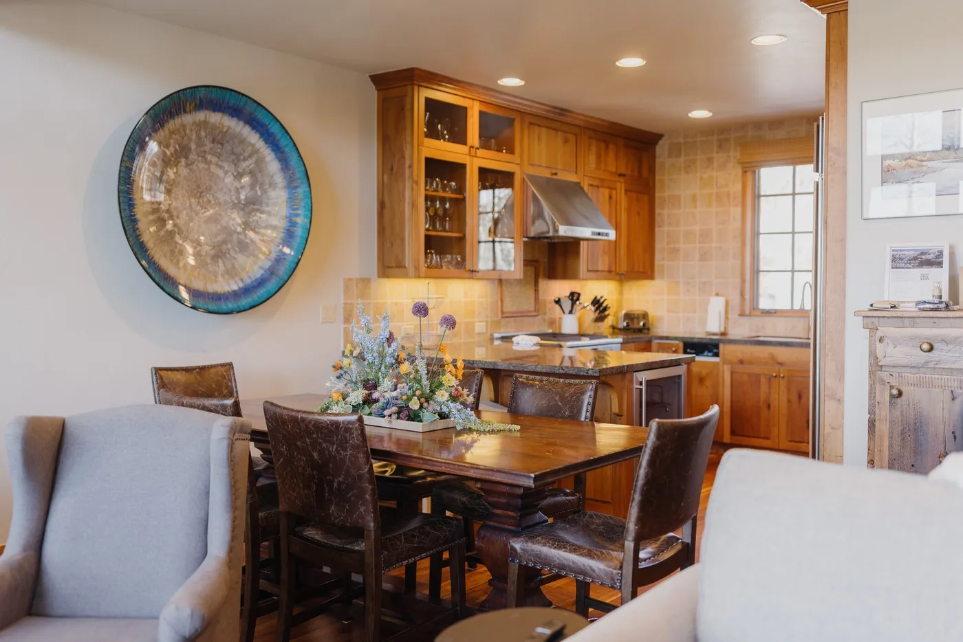 A dining area beside a kitchen, with a wooden table and cabinetry.