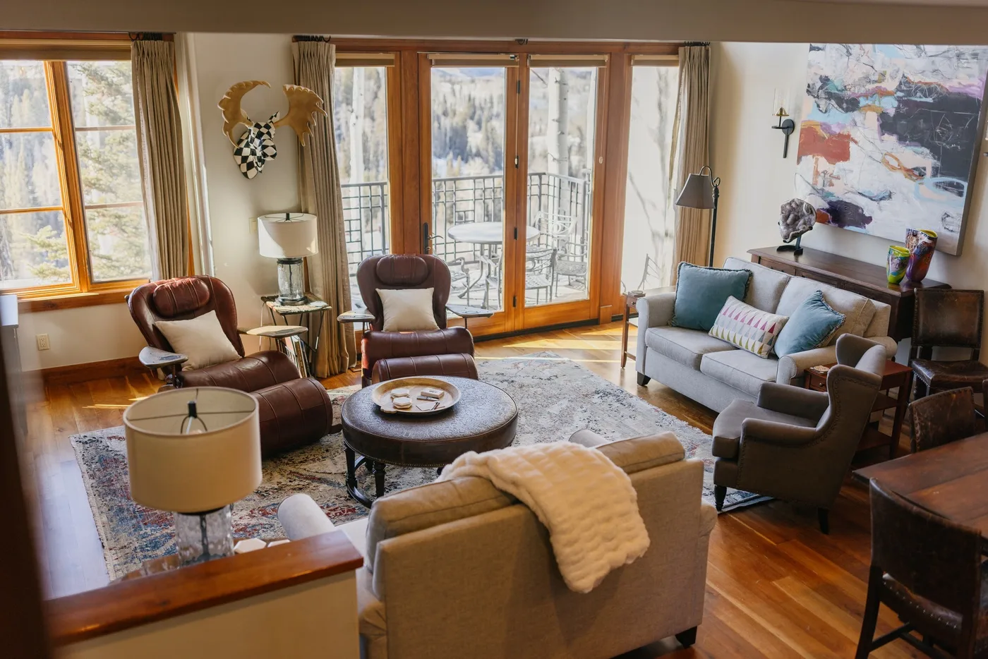 A bright living room with seating arranged around a low coffee table and large windows.