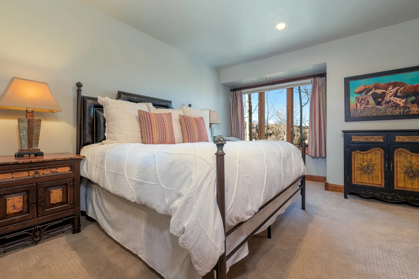 A bright bedroom with a neatly made bed and a large window.