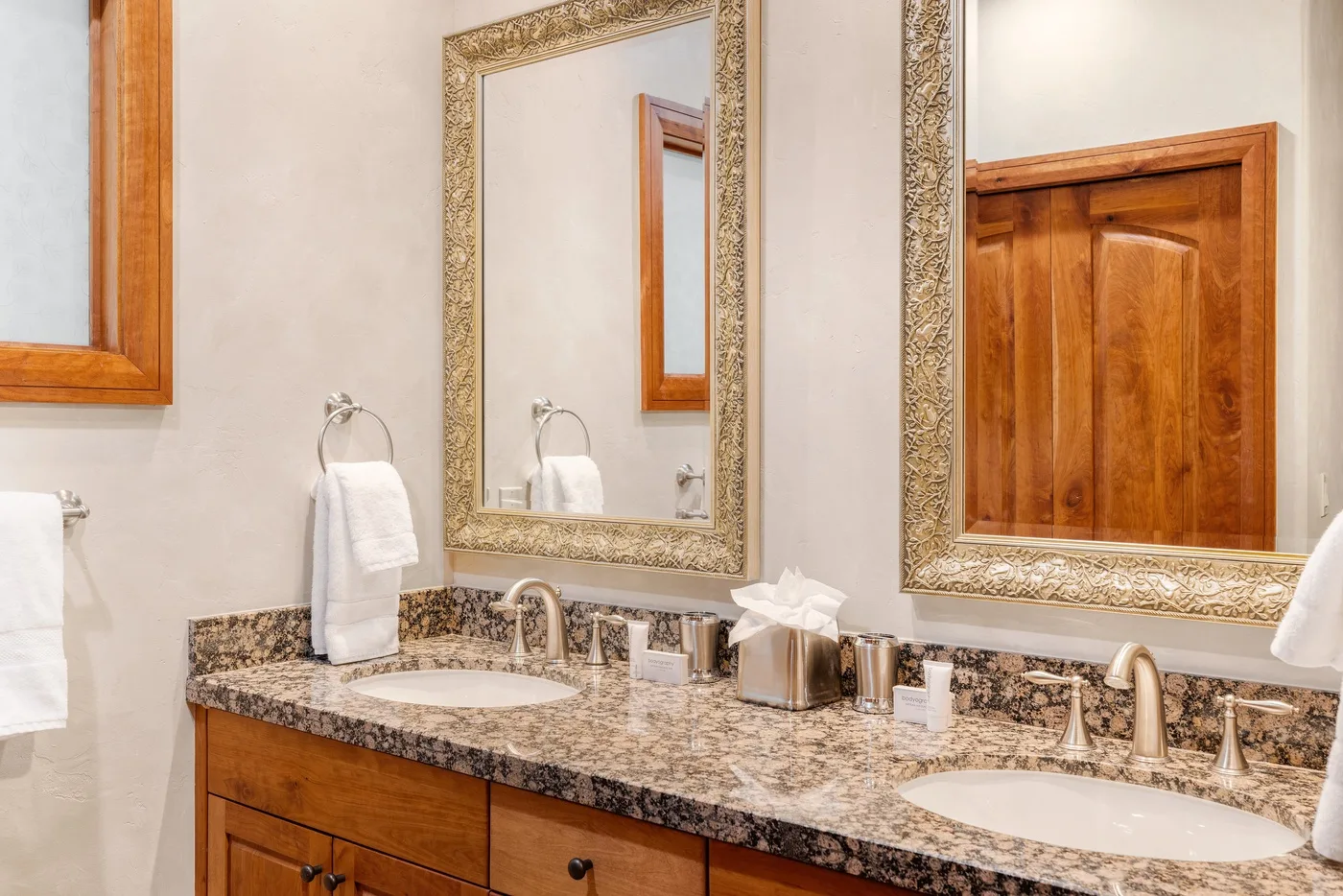 A bathroom vanity with two sinks, mirrors, and wooden cabinetry.