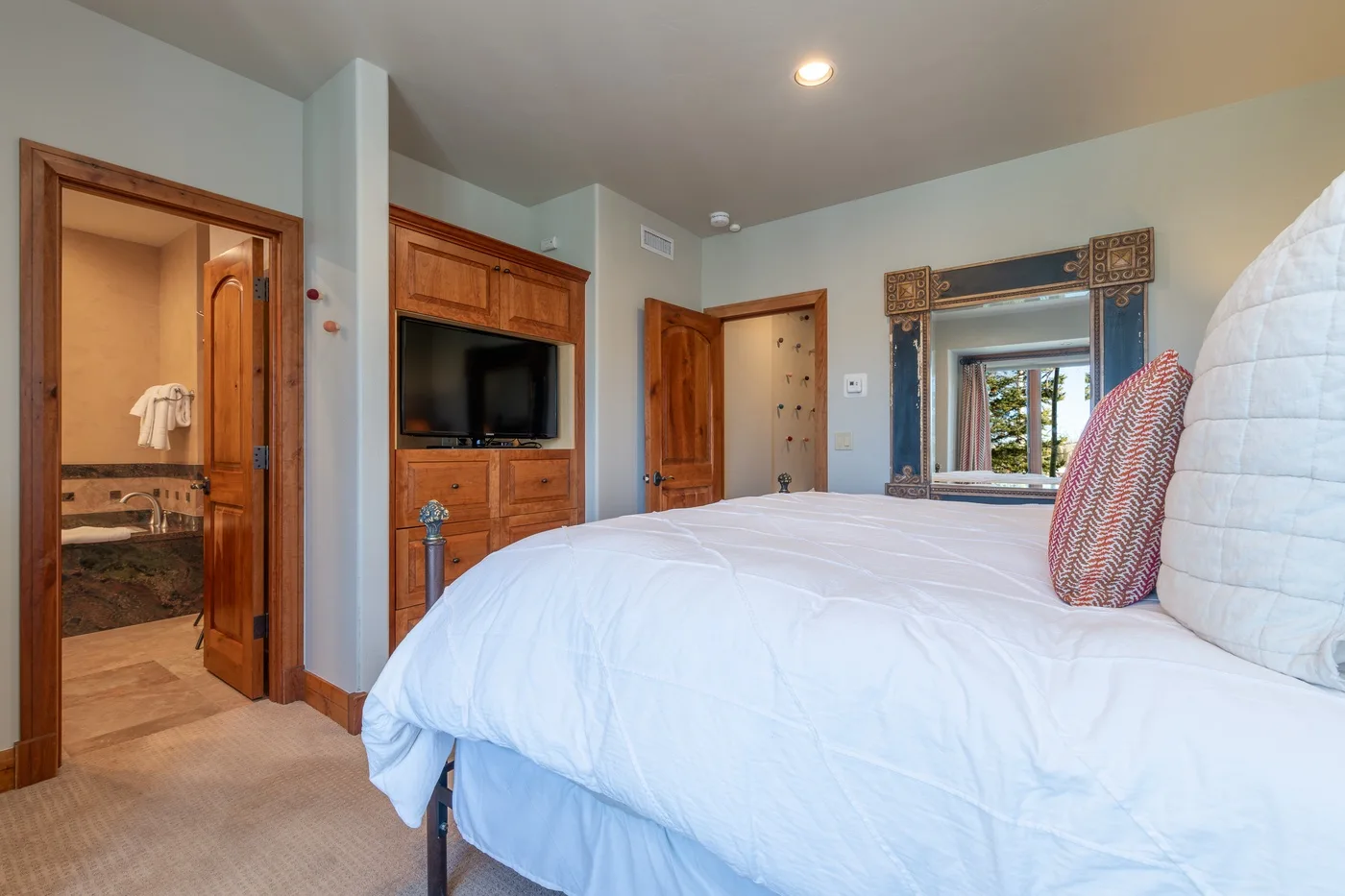 A bedroom with a large bed, wooden cabinetry, and a television.