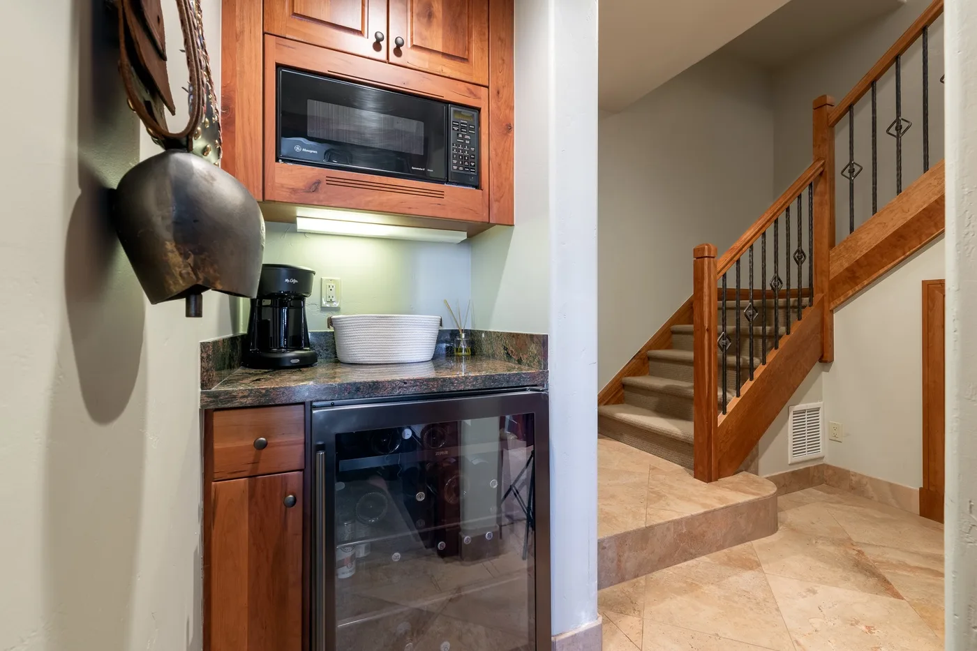 A compact kitchen nook with wood cabinetry sits beside a staircase.