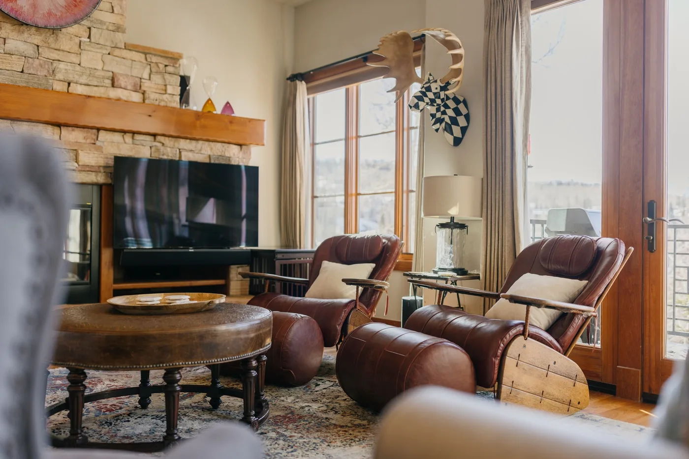 A living room with leather seating, a television, and a stone fireplace.