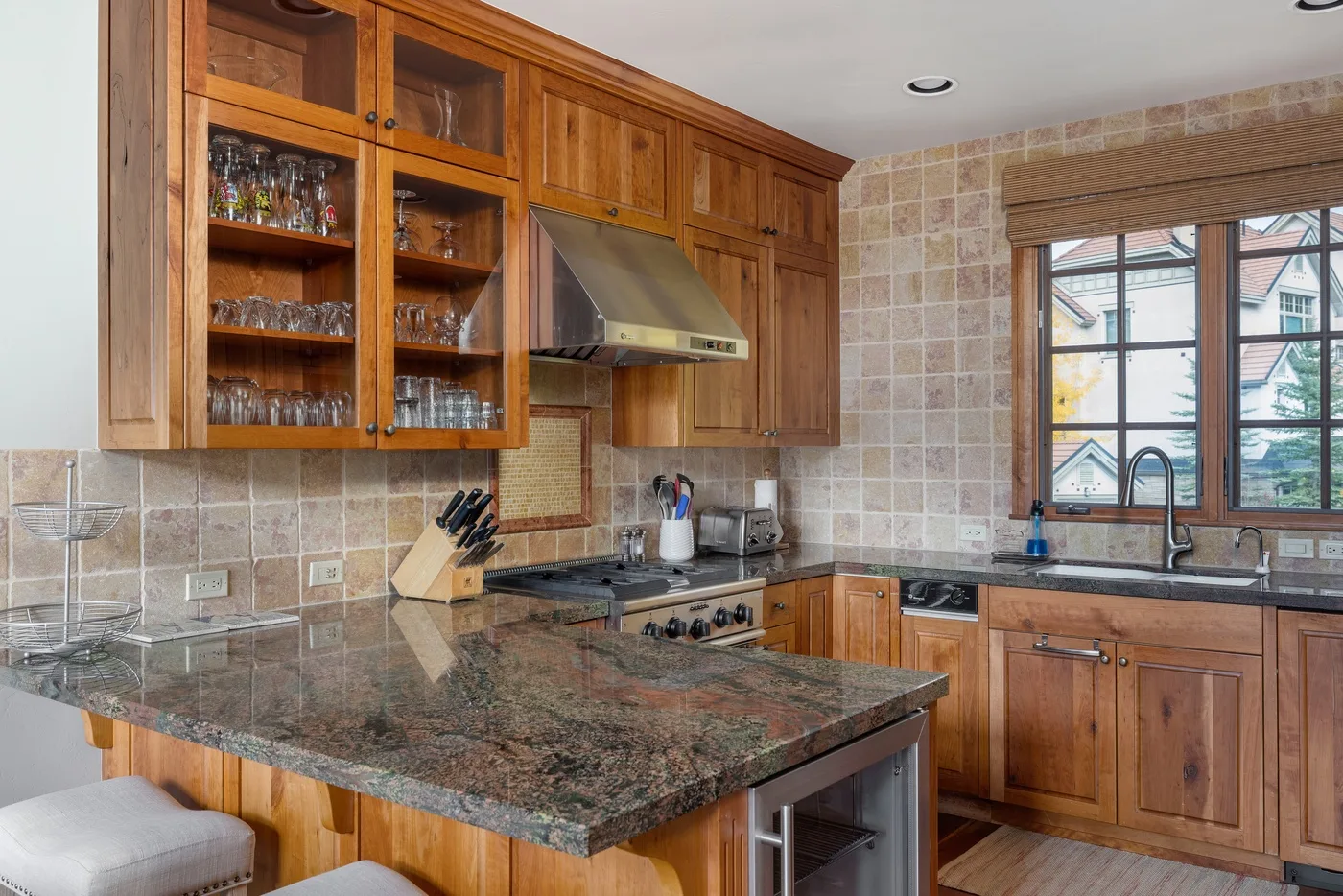 A kitchen with wooden cabinets, a central counter, and a window above the sink.