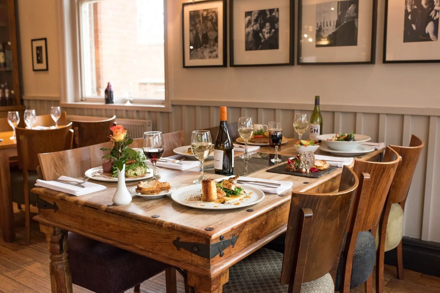 Restaurant table set with plated dishes, glasses and bottles.