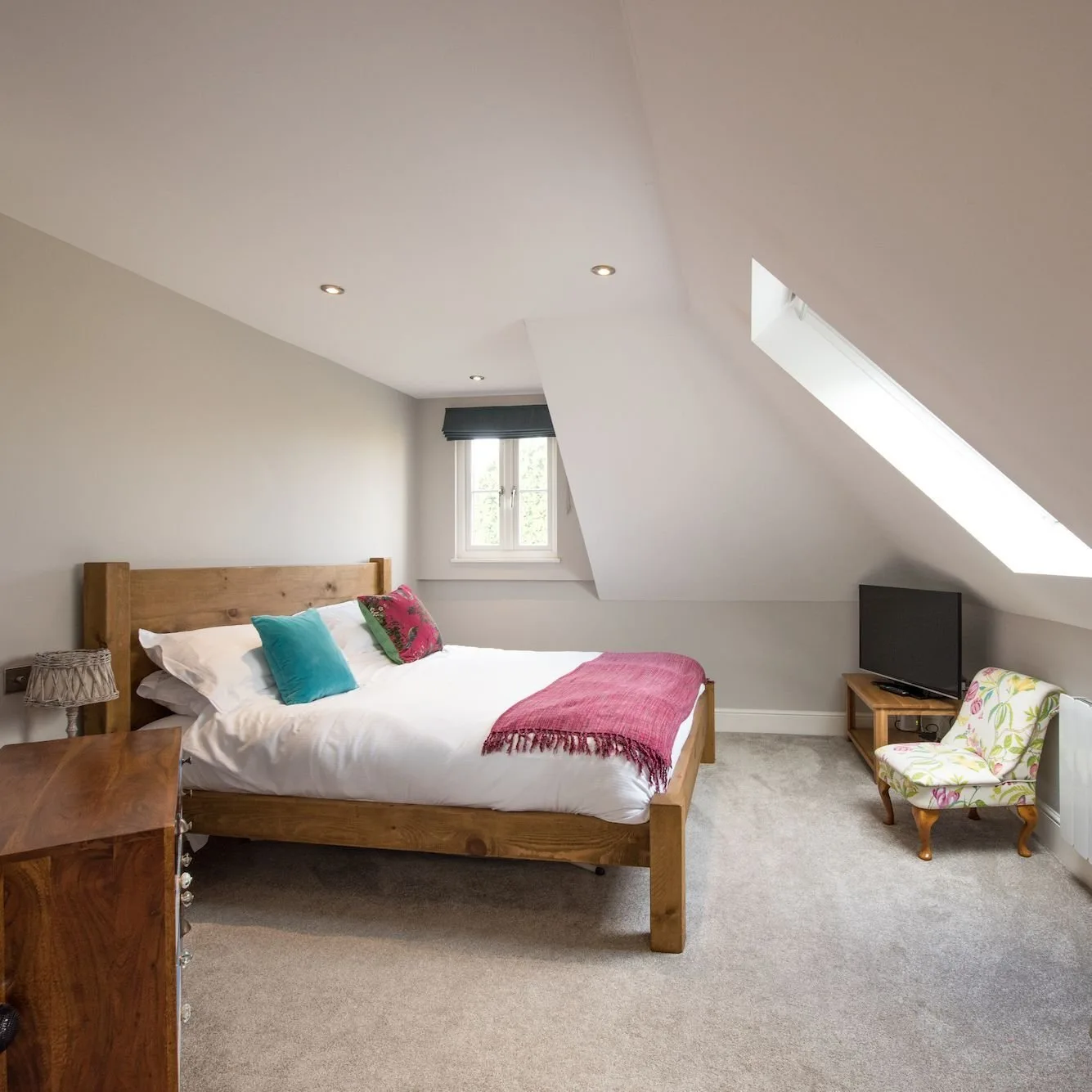 Bedroom beneath the eaves with a skylight and a floral armchair.