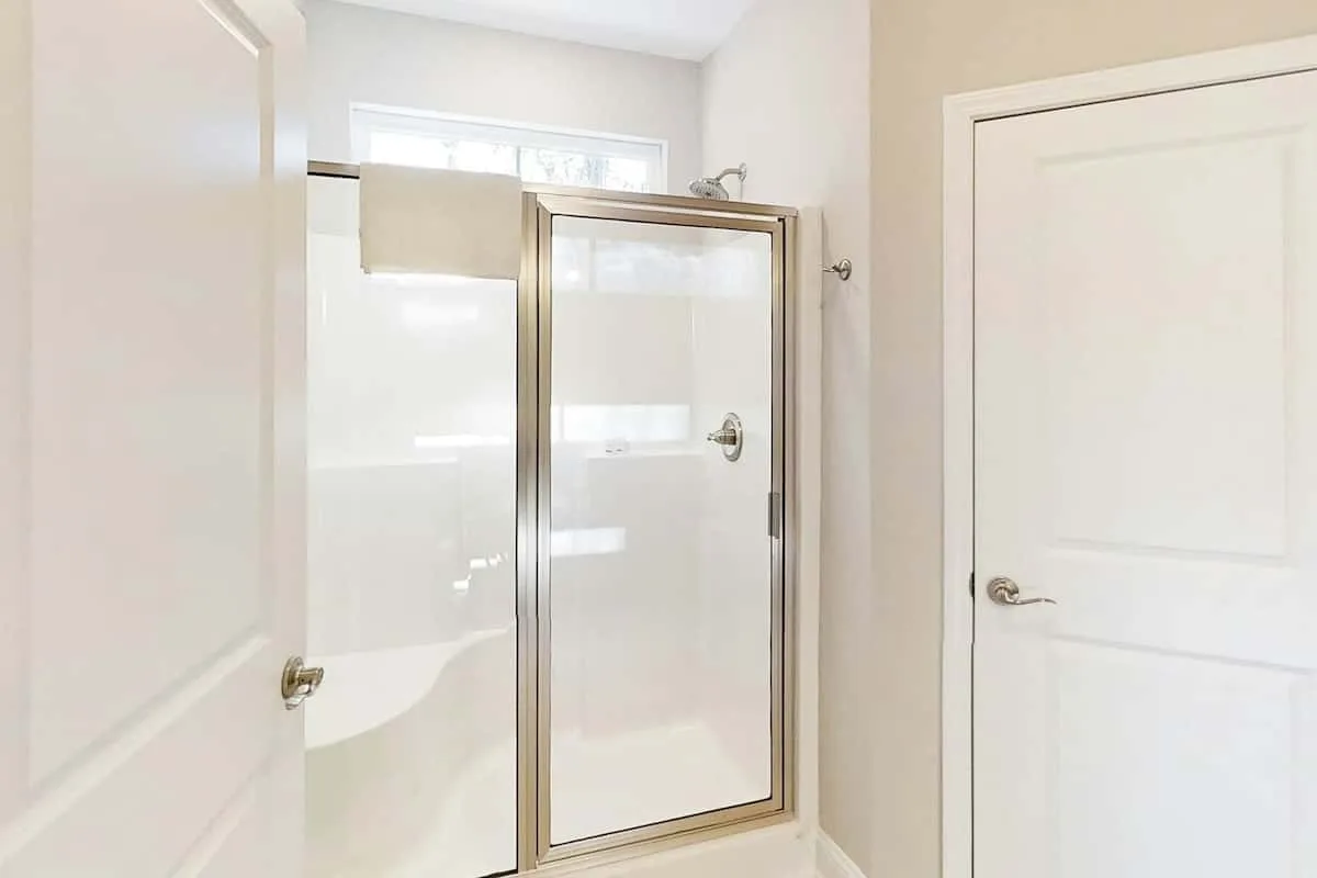 Un baño con una ducha de vidrio y puertas blancas.