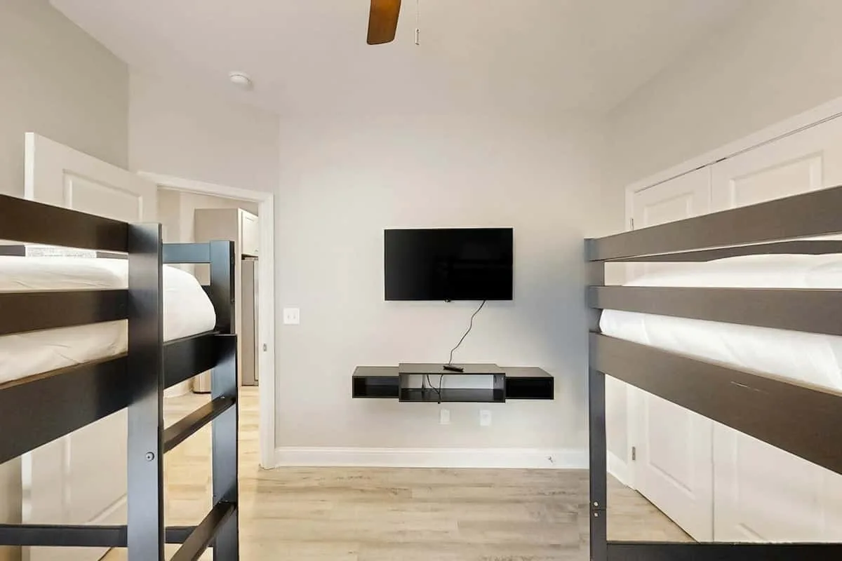 Un dormitorio con literas y un televisor montado en la pared.