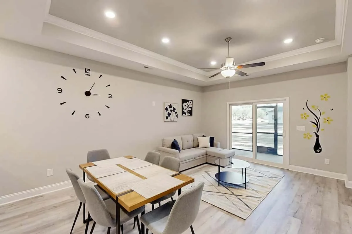 Una sala de estar y comedor con asientos, una mesa y puertas corredizas de vidrio.