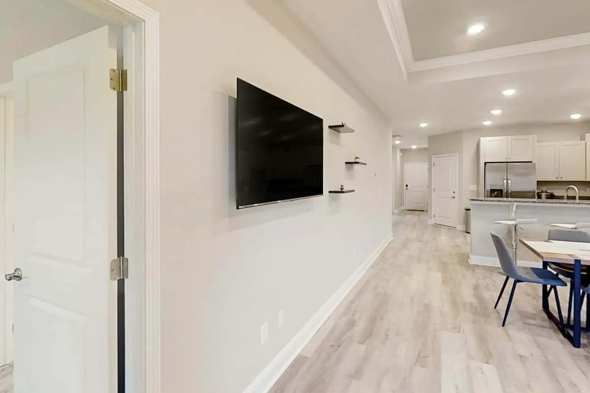 Una luminosa sala-comedor de concepto abierto, con un televisor en la pared y la cocina al fondo.