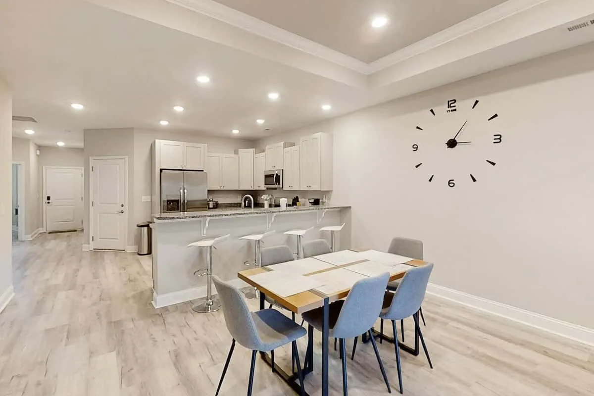 A bright open kitchen and dining area with a breakfast counter and table.