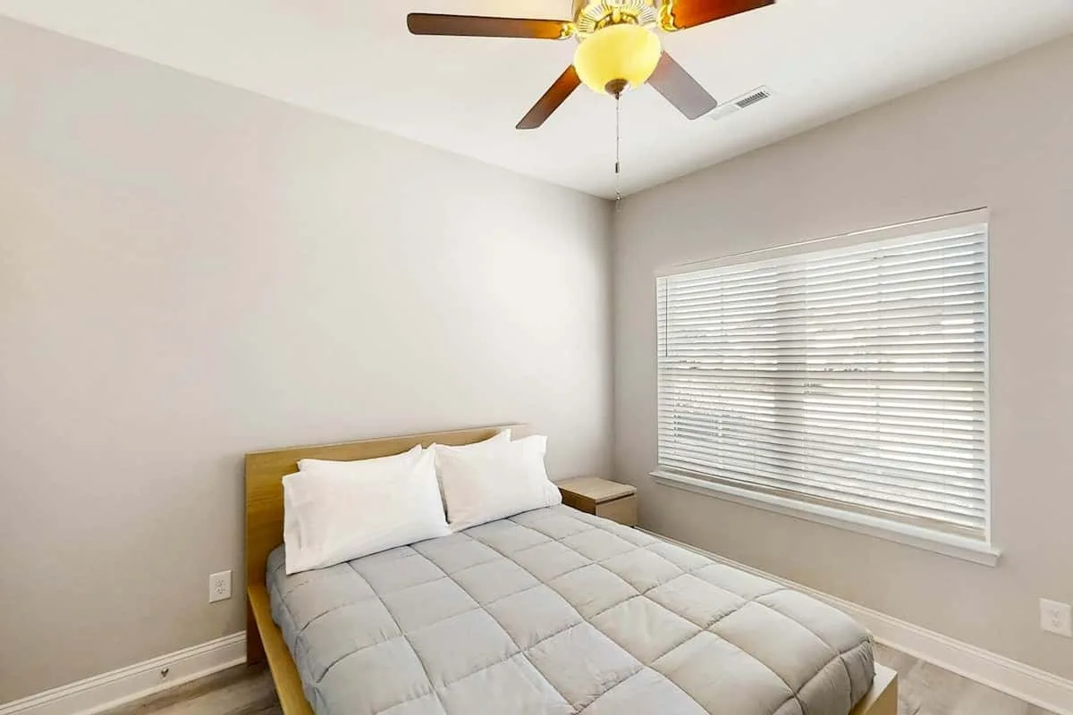 Un dormitorio con una cama bajo una ventana con persianas horizontales.
