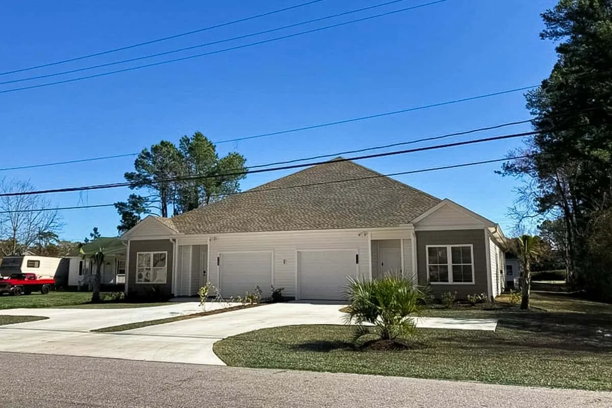 A single-story house with a wide driveway and small landscaped lawn.