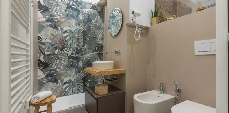 Un baño con lavabo, bidé y zona de ducha junto a un panel de vidrio estampado.