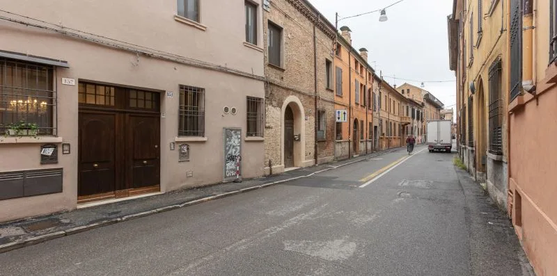 Una calle estrecha pasa entre edificios muy juntos, con una furgoneta de reparto a lo lejos.
