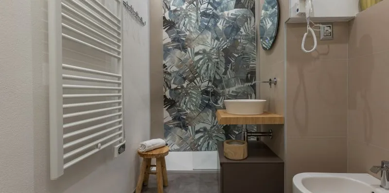 Un baño con lavabo, azulejos estampados y un radiador toallero.