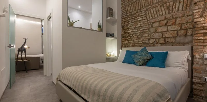 Un dormitorio con una cama frente a una pared de ladrillo visto.