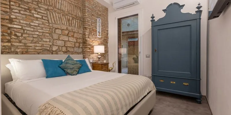 Un dormitorio con una cama, una pared de ladrillo visto y un armario azul.
