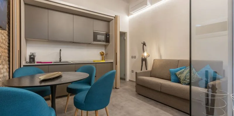 Sala y comedor integrados con una cocina compacta y asientos azules.