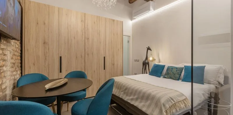 Un dormitorio con una cama grande, cojines azules y una mesa redonda.