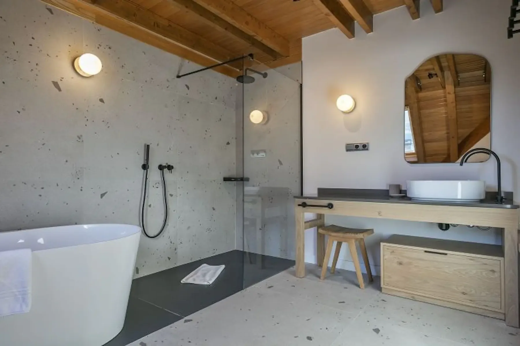 A bathroom with a freestanding bathtub, glass shower area, and wood vanity.