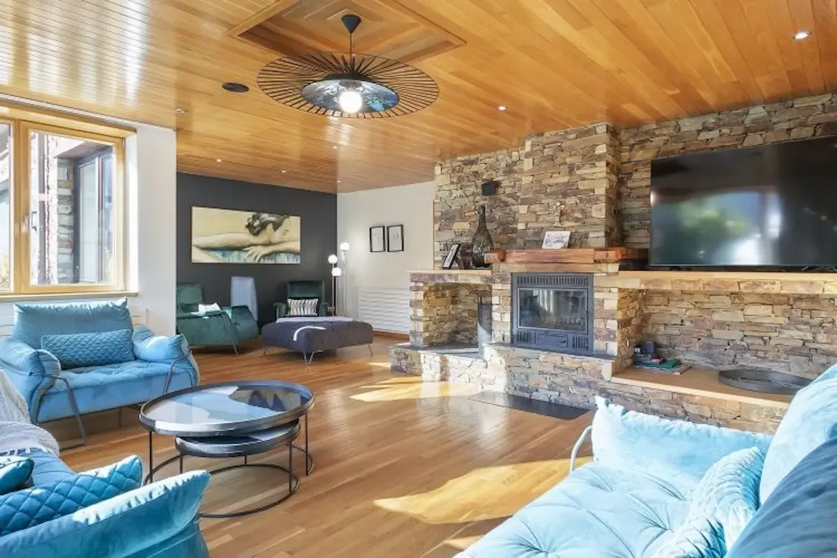 A bright living room with blue seating and a stone fireplace.