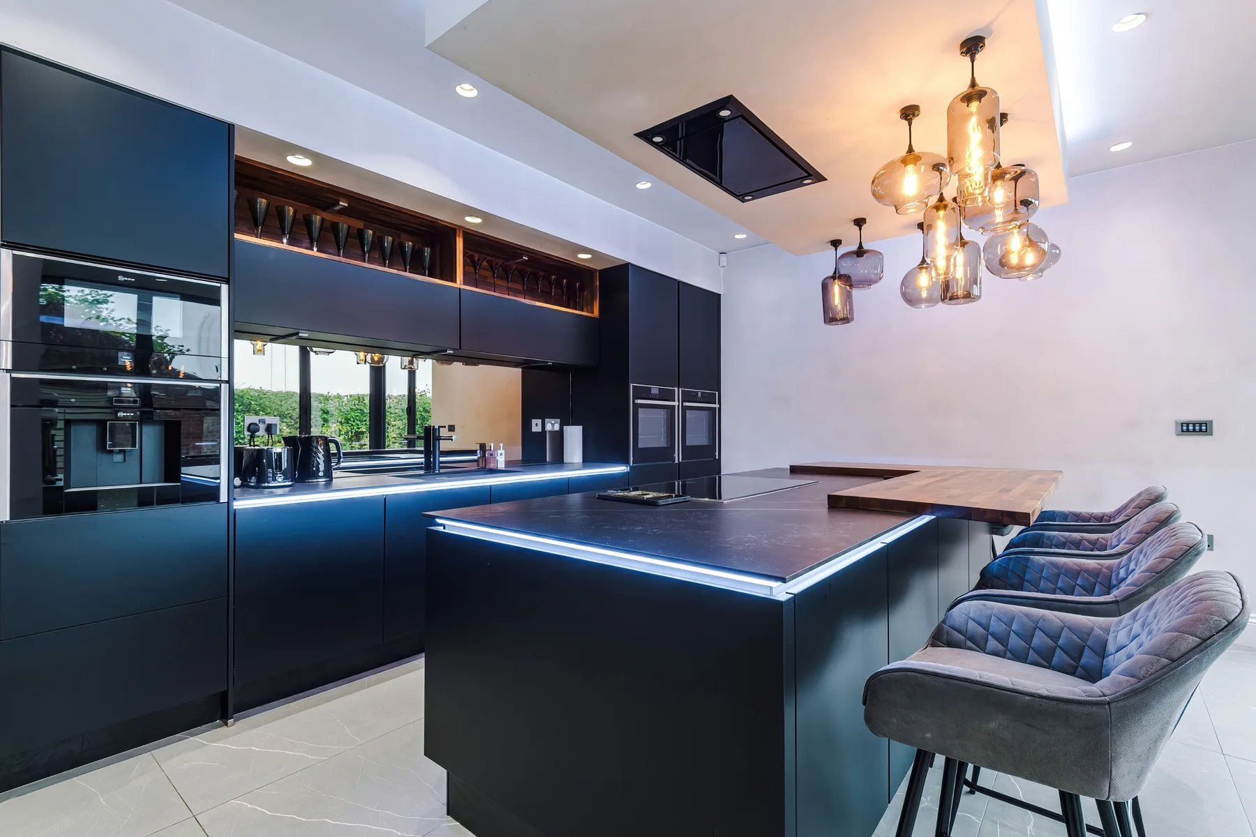 A modern kitchen with a large island and several stools.