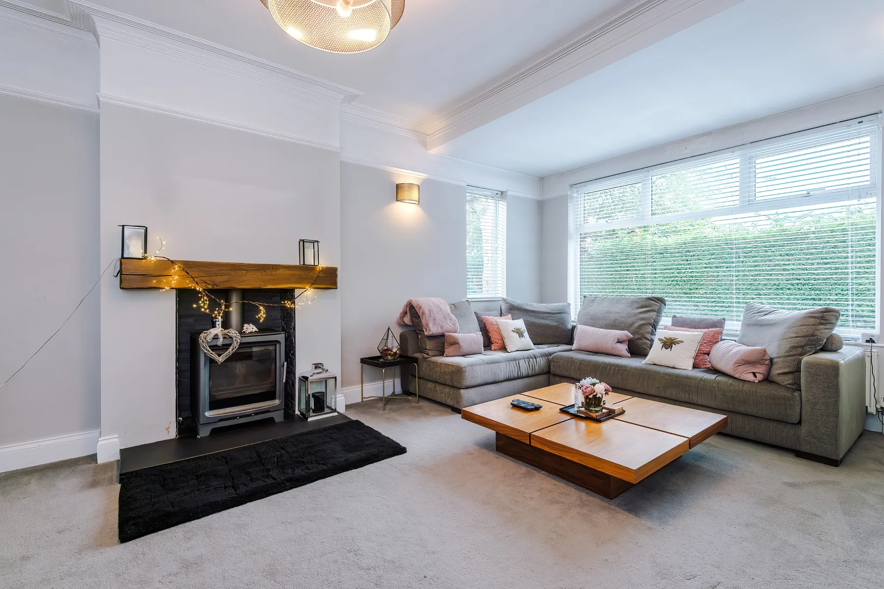 A bright living room with a fireplace and seating beside large windows.