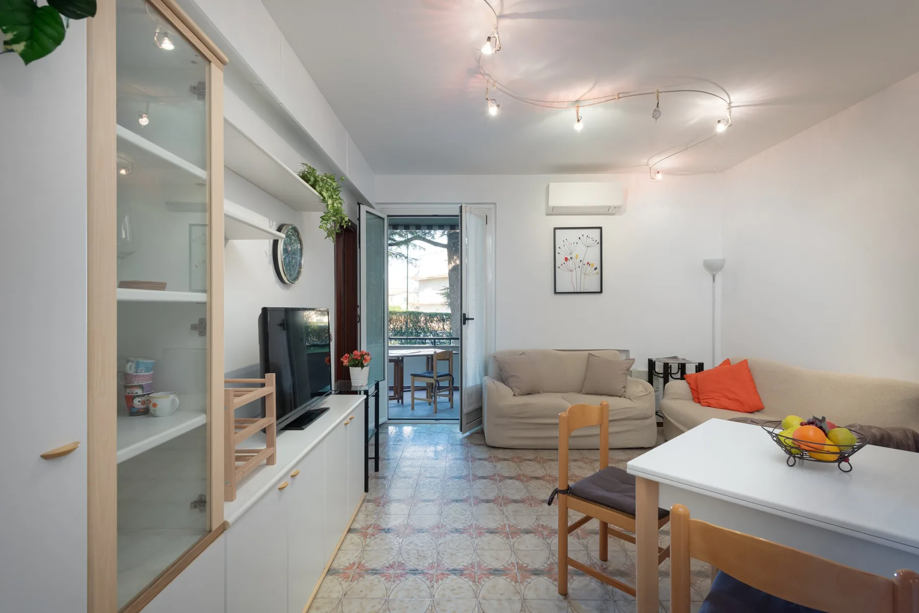 Una luminosa sala de estar y comedor con un sofá beige y una mesa blanca.