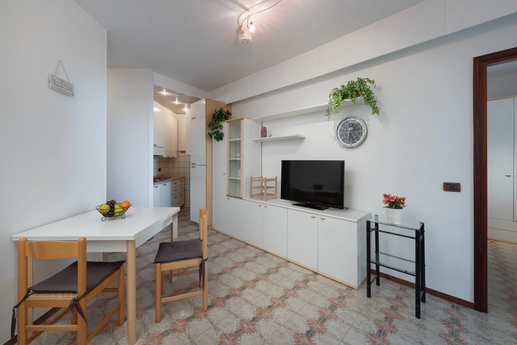 Una luminosa sala de estar y comedor con televisor, mesa y sillas.