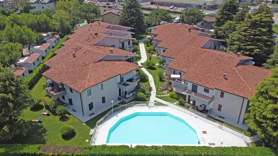 Vista aérea de edificios residenciales alrededor de una piscina y jardines.