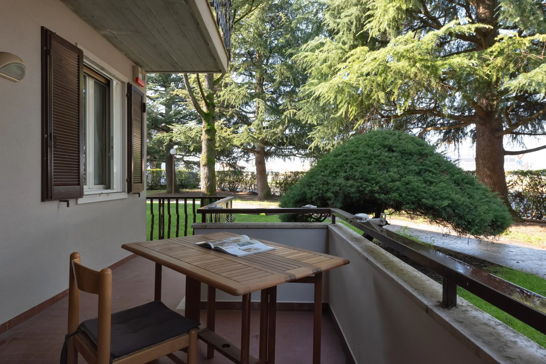 Un patio exterior cubierto con una mesa de madera y vegetación alrededor.