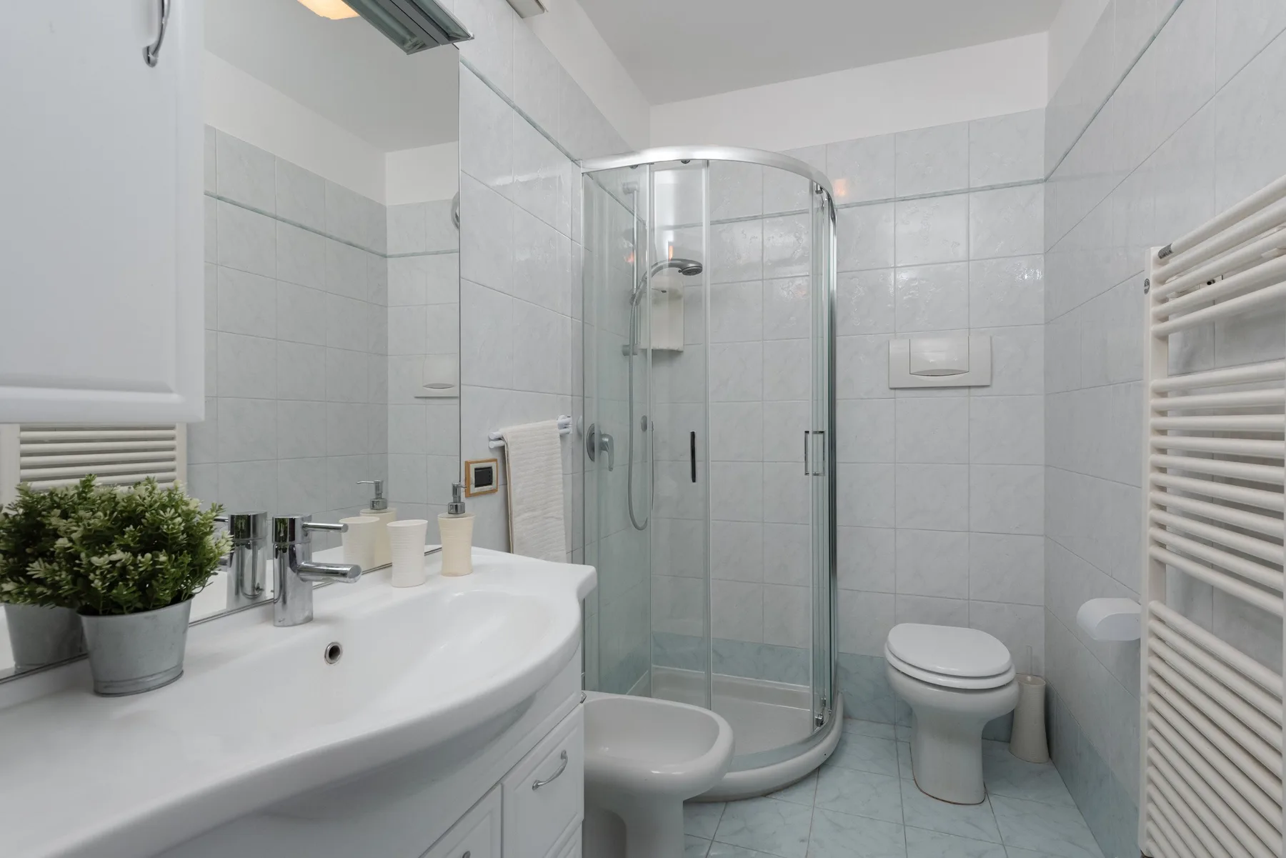 Un baño alicatado con una ducha de vidrio y un lavabo amplio.