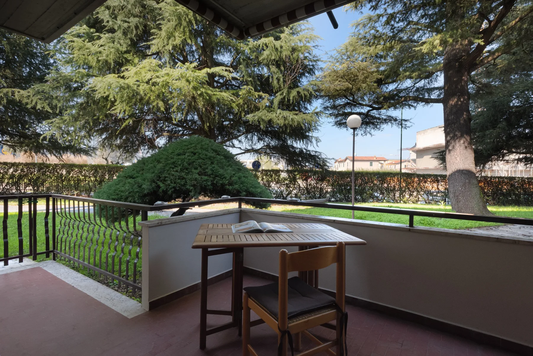 Una terraza exterior cubierta con una mesa de madera y vistas al jardín.