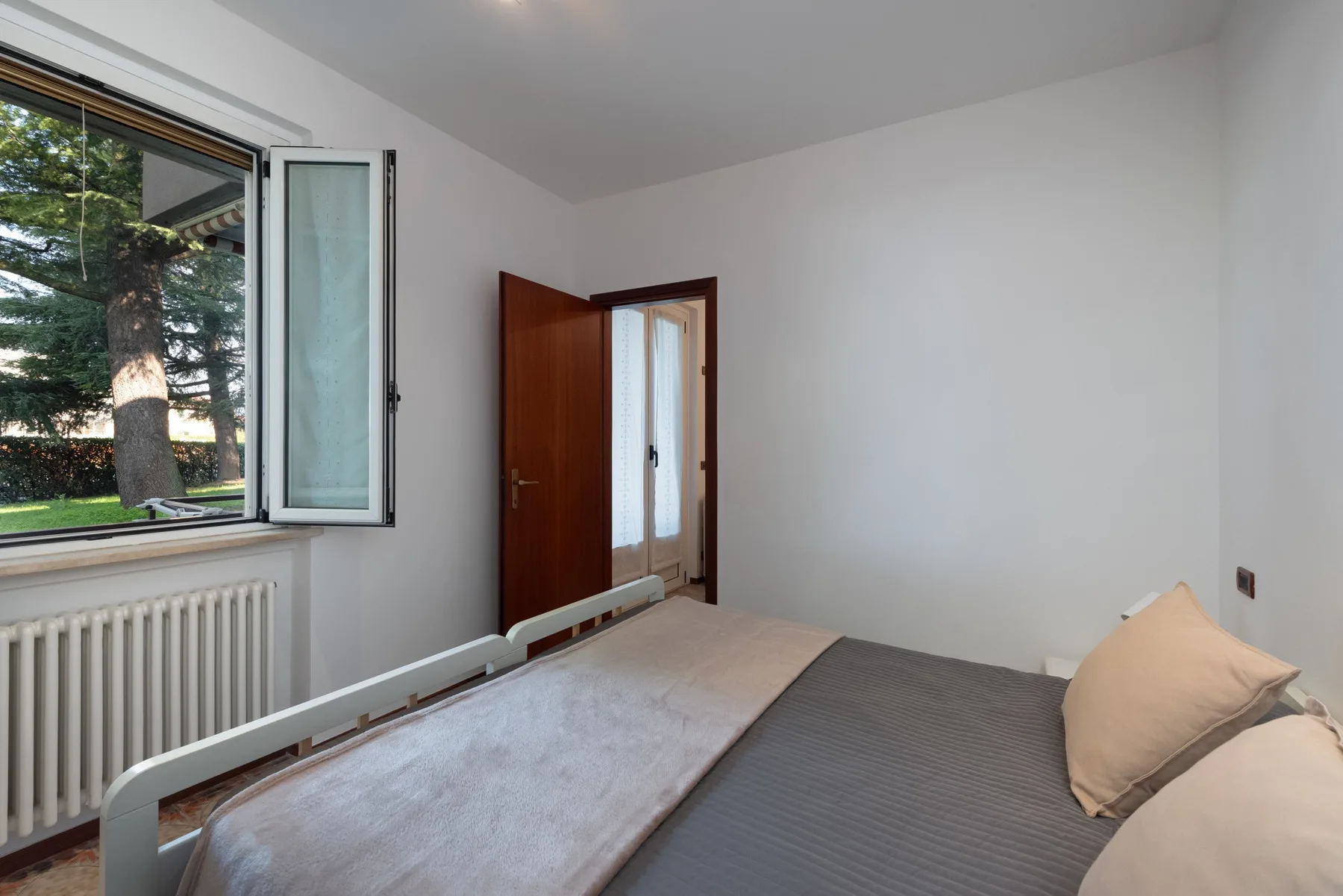 Un dormitorio con una cama junto a una ventana abierta.