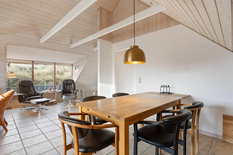 Un comedor con una mesa de madera y asientos bajo una lámpara colgante.