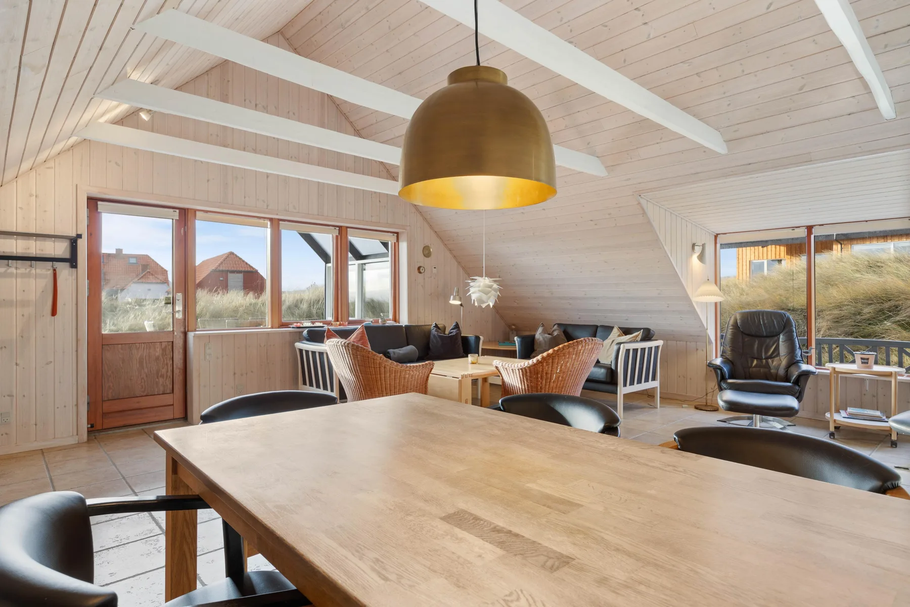 Una luminosa sala de estar y comedor con una mesa grande de madera y asientos.