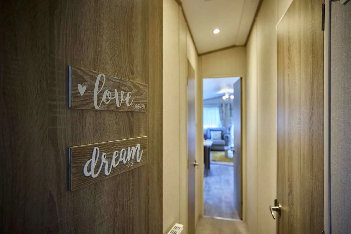 Un pasillo estrecho con puertas de madera y letreros decorativos en la pared.