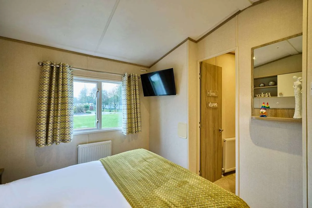 Un dormitorio con una cama, una ventana y un televisor en la pared.