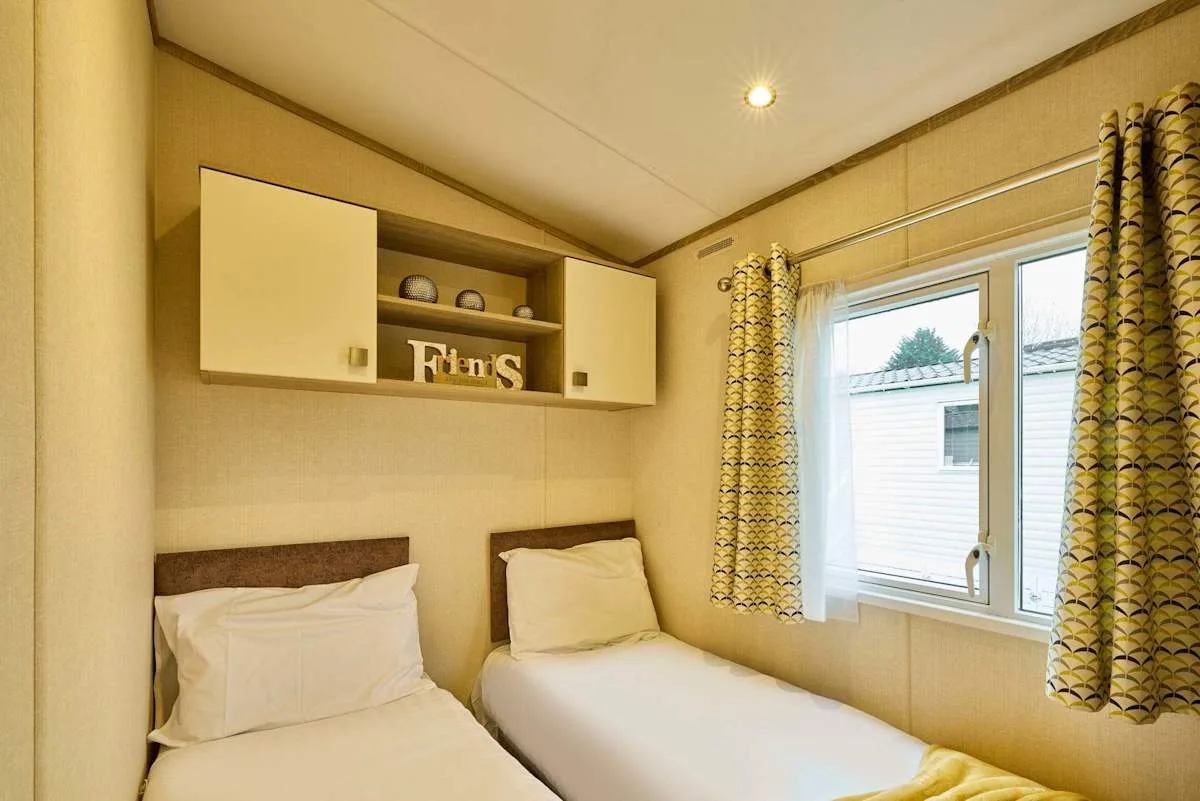 Un dormitorio con dos camas individuales, estantes en la pared y una ventana.