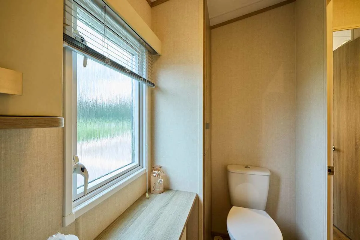 Un baño con una ventana y un inodoro junto a una encimera.